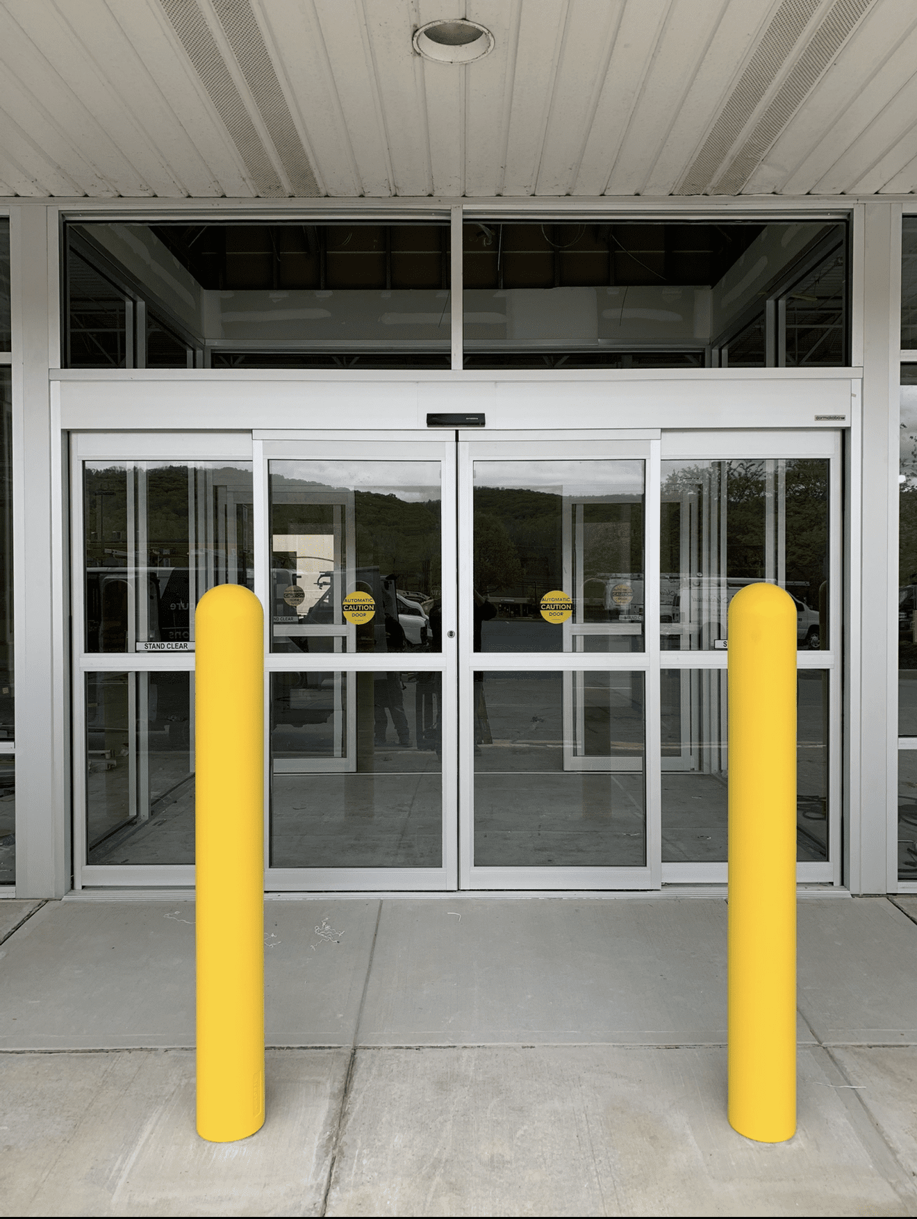 Glass doors with yellow bollards outside entrance.